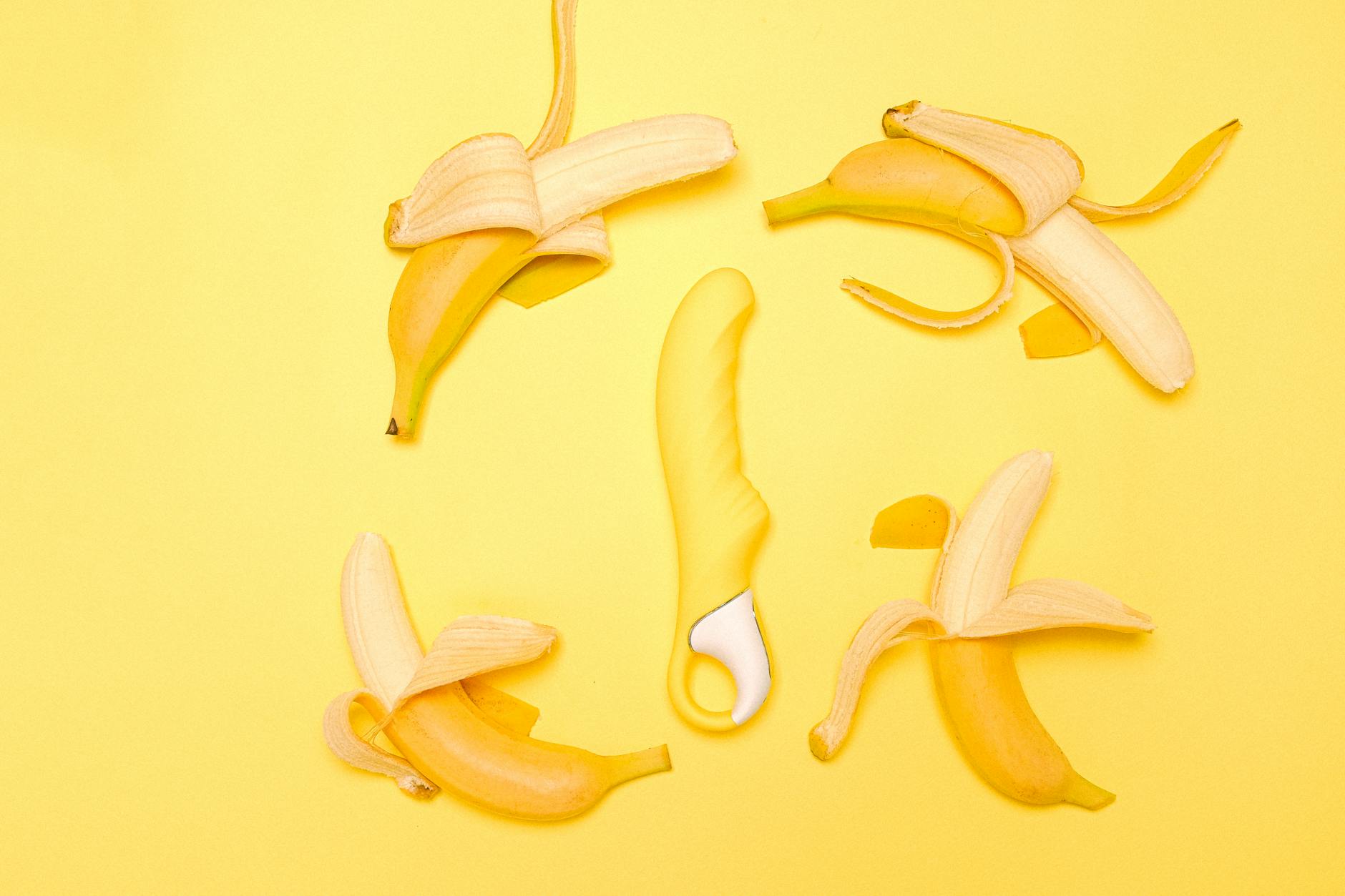 Yellow lemon vibrator surrounded by peeled bananas on a yellow background