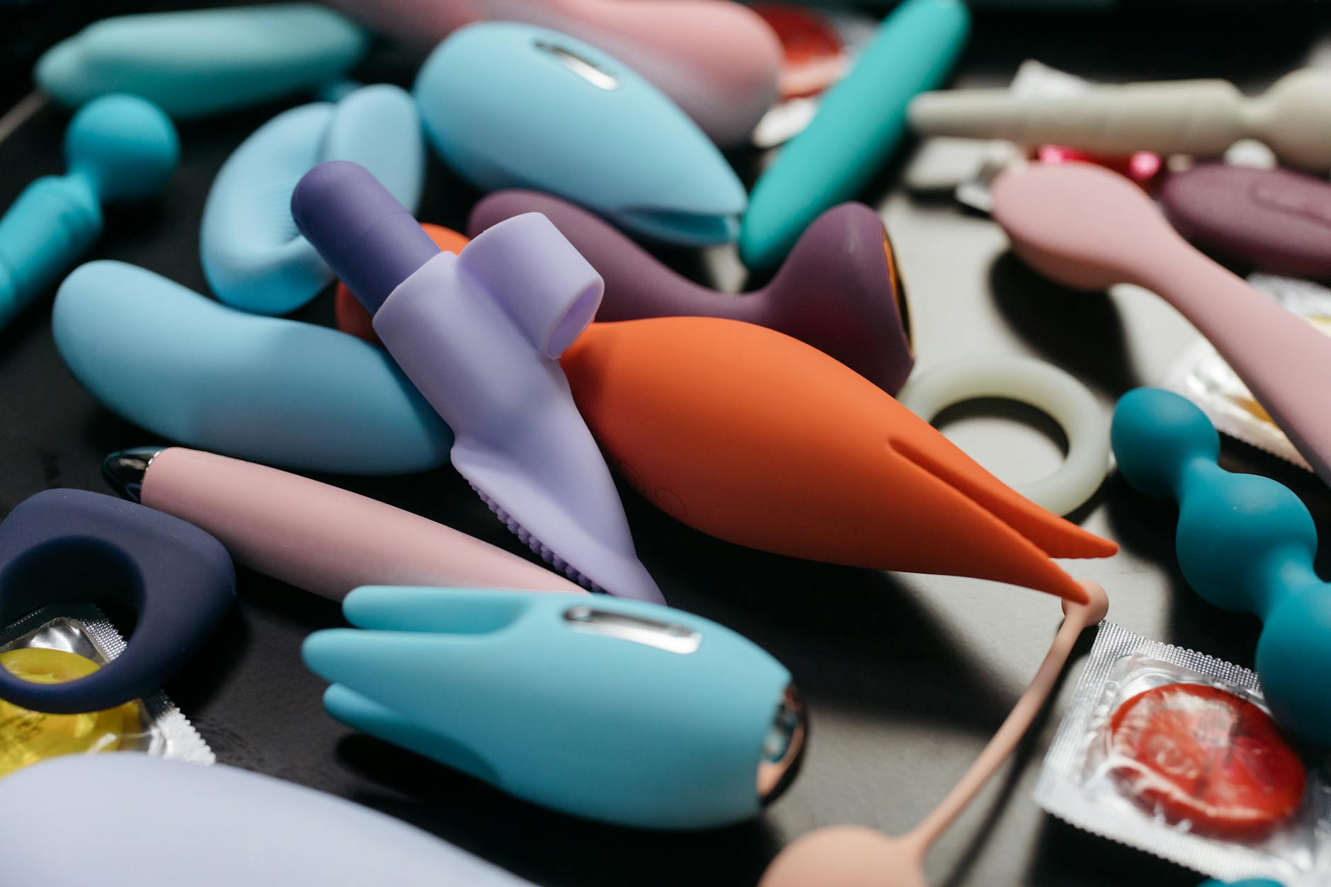 A hand holding a lemon-colored vibrator against a minimalist purple background